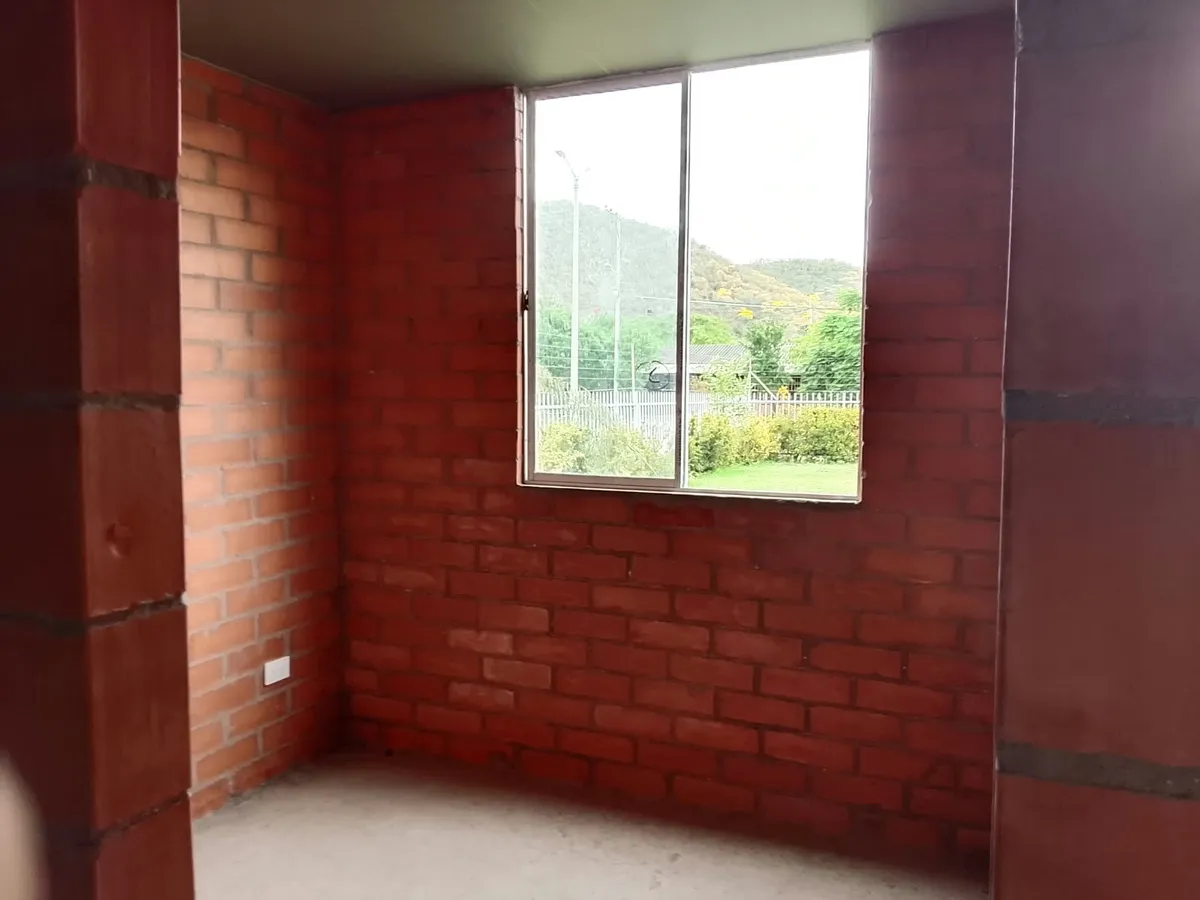 Alcoba en obra gris con ventana hacia las montañas
